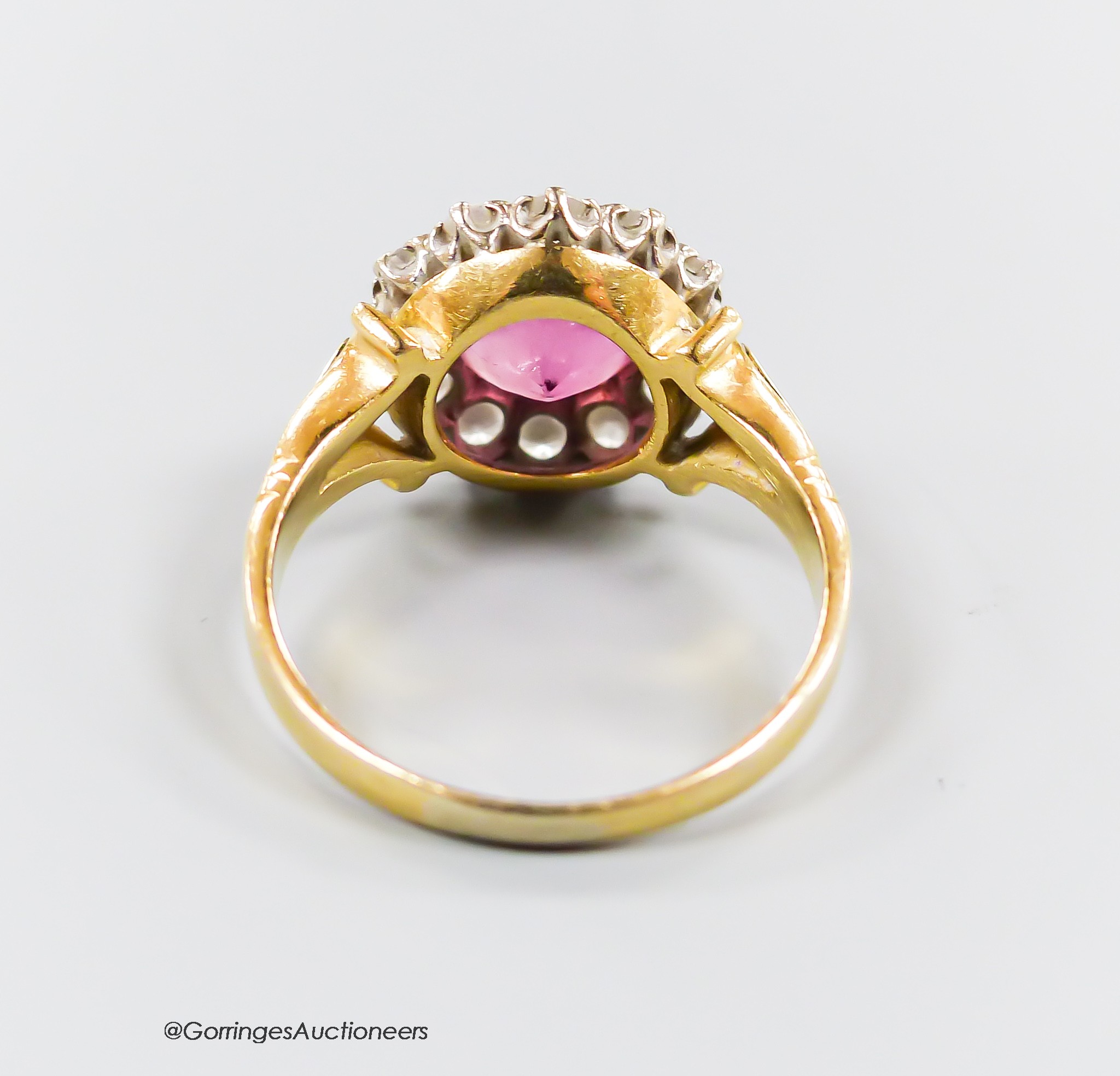 A modern yellow metal, pink tourmaline and diamond set circular cluster ring, size O, gross 5.1 grams.